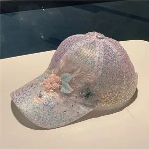 Detail view of 3D lace flowers and iridescent sequins on a white mesh baseball cap