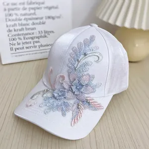 Detail of white satin baseball cap with floral embroidery and delicate pearls