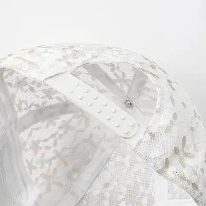 Detail aus weißem floralem Spitzenstoff mit verstellbarem Snapback-Verschluss der Kappe