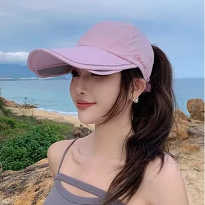 Detail of pink ponytail baseball cap showing retractable brim and letter embroidery