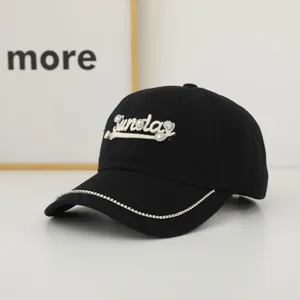 Detail of Sunday embroidery with sparkling rhinestones on black cotton baseball cap