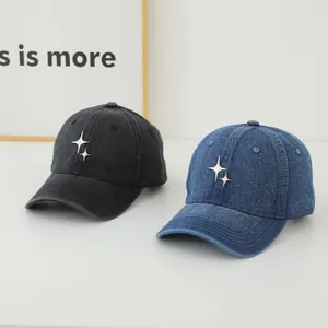 Detail of washed denim baseball caps in black and navy blue with metal star badge