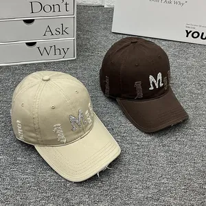 Detail of vintage distressed baseball caps with sparkling M embroidery in beige and brown