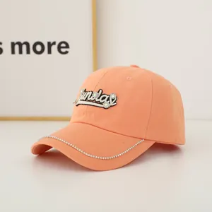Detail of bright orange baseball cap with rhinestone-studded Sunday embroidery on crown