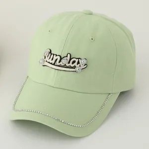Detail of mint green baseball cap with Sunday embroidery and sparkling rhinestone brim