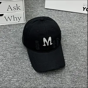 Detailed view of black baseball cap with rhinestone M letter and distressed torn accents