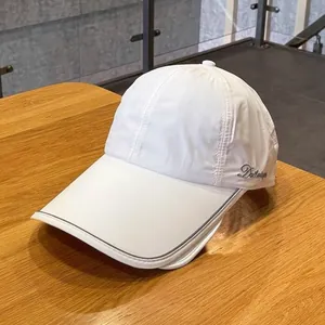 White quick-dry baseball cap with extended brim and side embroidery on wood table