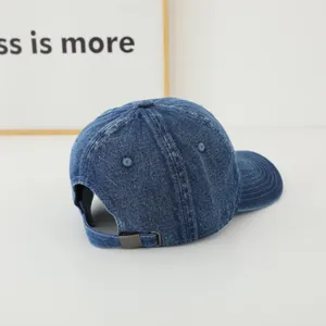 Detail of adjustable metal buckle and washed denim texture on blue baseball cap