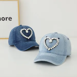 Detail von dunkel- und hellblauen Denim-Baseballkappen mit Herz-Rheinstein-Verzierung