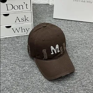 Detail of distressed dark brown baseball cap with white M embroidery and frayed edge design