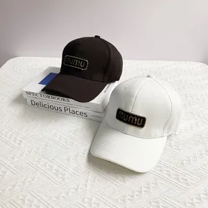 Fashionable mumu logo baseball caps in black and white colors on decorative books