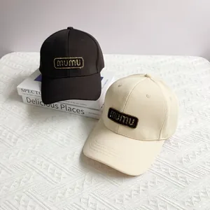 Fashionable baseball caps in black and beige with mumu letter patch and metallic trim
