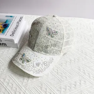Close-up of white lace baseball cap featuring shimmering rhinestone butterfly and LOVE design