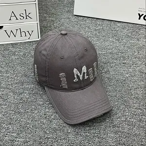 Close-up of distressed denim baseball cap with rhinestone M letter and frayed details