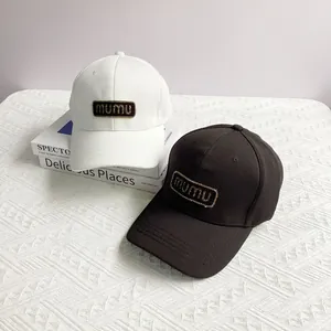 Detail of white and black baseball caps with mumu patches on a minimalist book background
