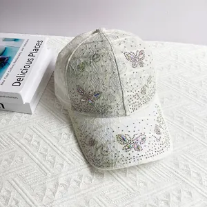Detail of off-white lace baseball cap featuring iridescent rhinestone butterfly and Love script