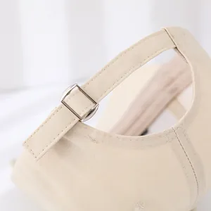 Close-up of adjustable metal buckle and canvas texture on beige baseball cap