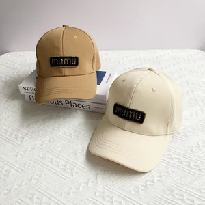 Detail view of khaki and cream baseball caps with mumu logo on textured pineapple fabric