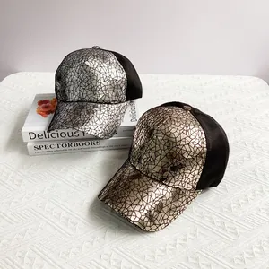 Close-up of geometric sequin patterns on metallic silver and gold baseball caps with mesh back