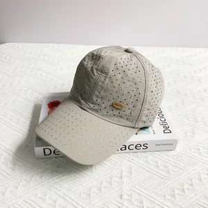 Detail of light gray laser-cut breathable holes and gold metal logo on baseball cap
