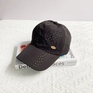 Close-up of black breathable baseball cap with laser-cut holes and gold metal logo