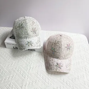 Détail de la casquette en dentelle avec fleurs en strass et broderie Kiss brillante