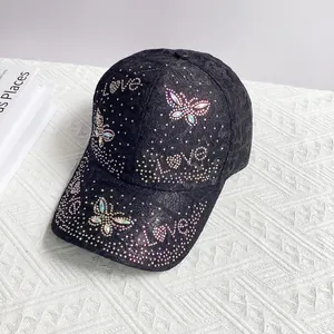 Close-up of black lace baseball cap with iridescent rhinestone butterfly and Love script
