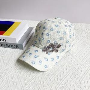 Detailed close-up of white lace baseball cap with blue geometric print and crystal butterflies