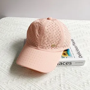 Detail of pink breathable baseball cap with laser-cut holes and gold metal logo