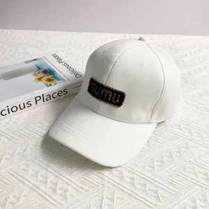 Close-up of white baseball cap with mumu letter patch and glitter gold finish