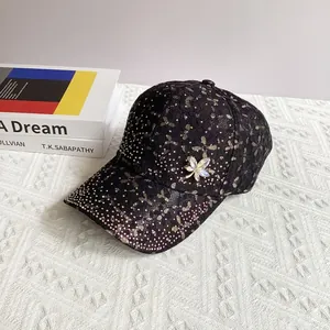 Close-up of black lace baseball cap with sparkling rhinestones and crystal leaf brooch