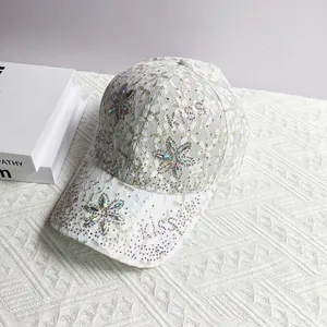Détail d'une casquette blanche en dentelle avec lettres KISS en strass et motifs floraux