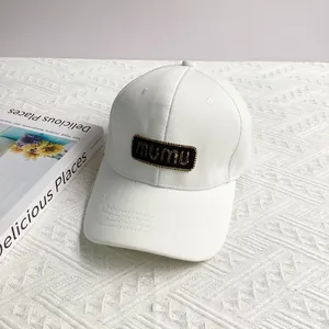 Detail of white cotton baseball cap featuring black mumu embroidered patch on pineapple fabric