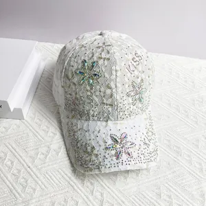 Détail de la casquette en dentelle blanche avec fleur en strass et cristaux