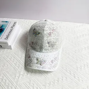 Detailed view of white lace baseball cap featuring colorful rhinestone butterfly and Love motif