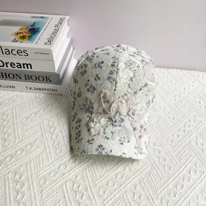 Close-up of white lace baseball cap featuring purple floral prints and pearl embroidery