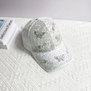 Detail of white lace baseball cap with rhinestone butterfly and Love lettering