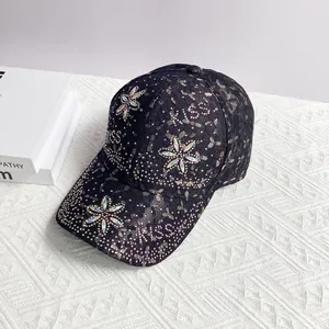 Détail de la casquette en dentelle noire avec fleurs en strass colorés et lettrage KISS brillant