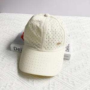 Detail of off-white baseball cap showing laser-cut breathability holes and gold metal logo