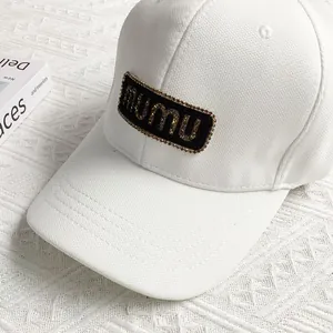 Close-up of white canvas baseball cap featuring a black mumu logo patch on the crown