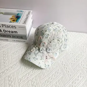 Detail of white lace baseball cap featuring blue floral print and 3D flower embroidery