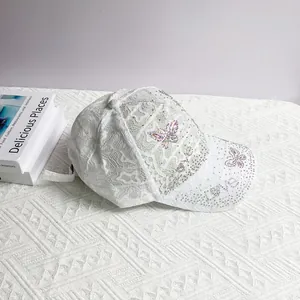 Close-up of white lace baseball cap with colorful rhinestone butterfly and LOVE letter detail