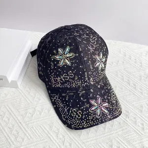 Détail de casquette en dentelle noire avec fleurs en strass colorées et lettrage KISS