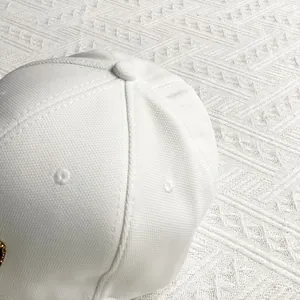 Macro detail of white canvas baseball cap showing six-panel stitching and embroidered eyelets