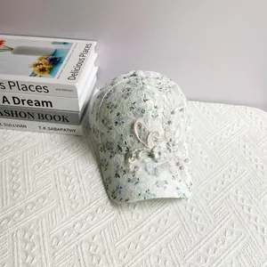Detail of white lace baseball cap featuring blue floral print and 3D flower embroidery