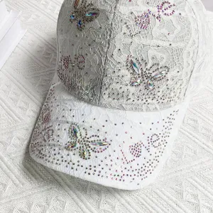 Close-up of white lace baseball cap with butterfly rhinestone design and LOVE pattern