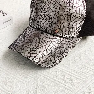 Detail of silver cracked metallic texture and breathable black mesh on baseball cap