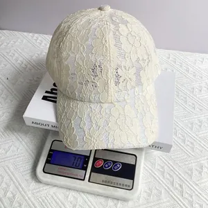 Détail d'une casquette en dentelle beige légère de 70g sur une balance montrant son poids