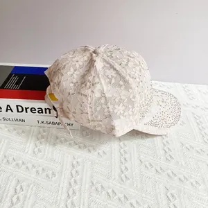 Detailed view of white lace baseball cap featuring rhinestones and metal buckle strap