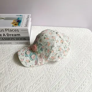 Vue détaillée de casquette de baseball avec fleurs 3D et dentelle sur une table blanche